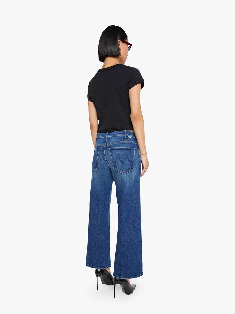 Back view of a petite woman in a med blue wide leg jeans with a high rise, zip fly, double-stitched side seam, 29-inch inseam and a clean hem.