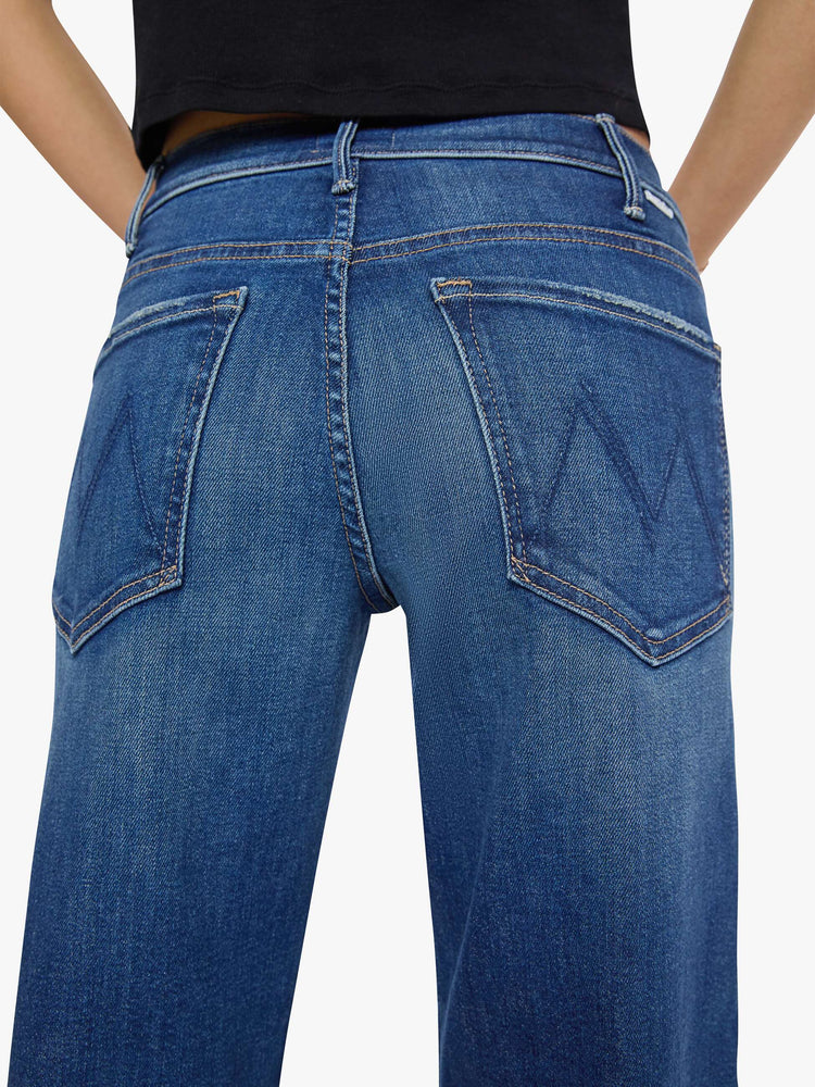 Close up view of a petite woman in a med blue wide leg jeans with a high rise, zip fly, double-stitched side seam, 29-inch inseam and a clean hem.