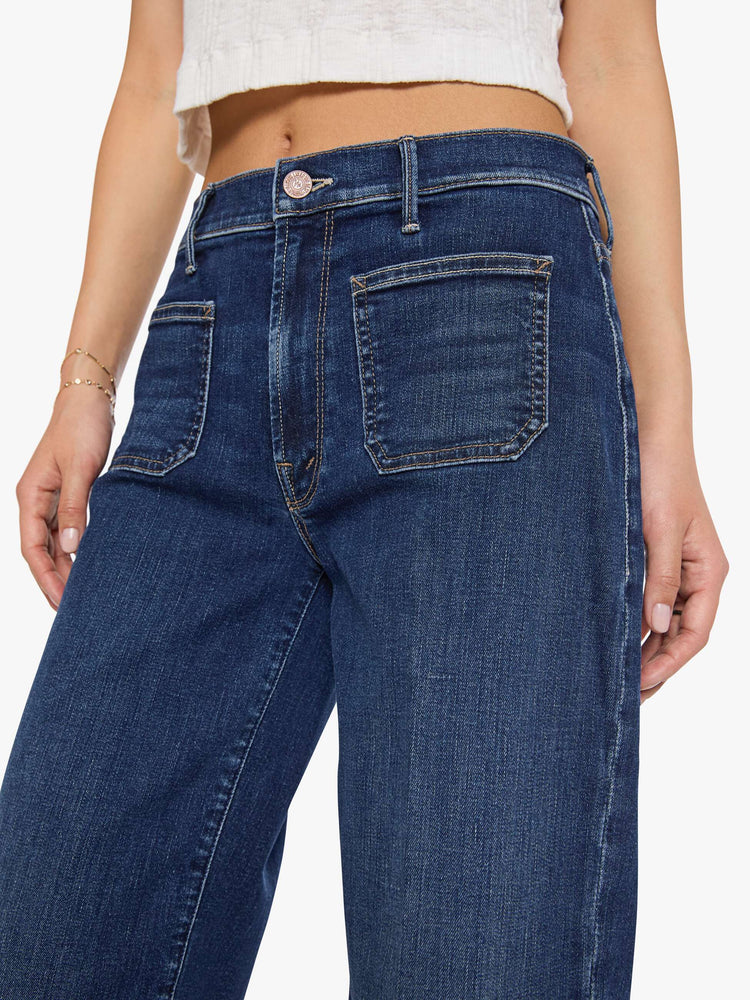 Close up view of a woman in a dark blue mid-rise jeans with a loose fit, wide leg, patch pockets, zip fly and 29-inch inseam with a clean hem.