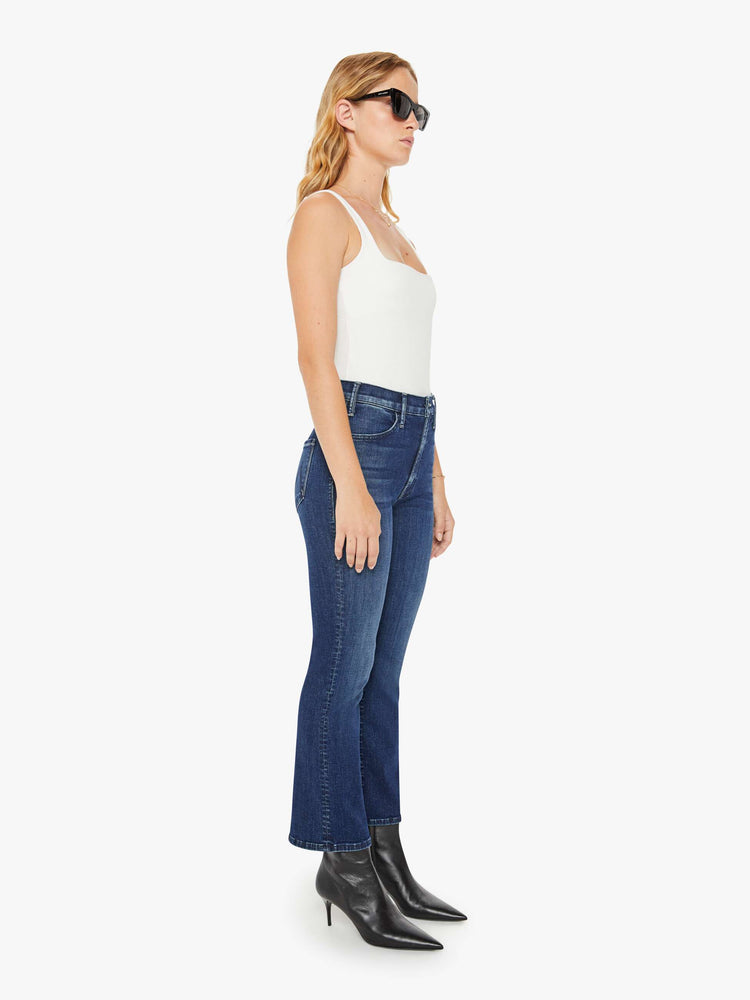Front view of a petite woman in a dark blue wash high-rise flare has an ankle-length inseam and a clean hem. 