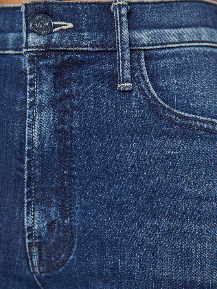 Swatch  view of a petite woman in a dark blue wash high-rise flare has an ankle-length inseam and a clean hem. 