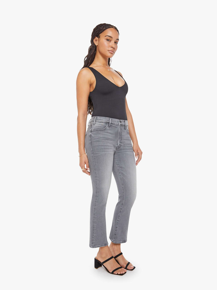 Side angle view of a petite woman in a grey high-rise flare has a zip fly, ankle-length inseam and a clean hem.