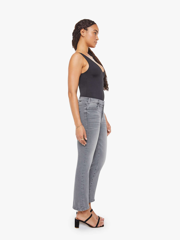 Side view of a petite woman in a grey high-rise flare has a zip fly, ankle-length inseam and a clean hem.