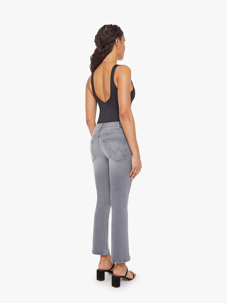 Back view of a petite woman in a grey high-rise flare has a zip fly, ankle-length inseam and a clean hem.