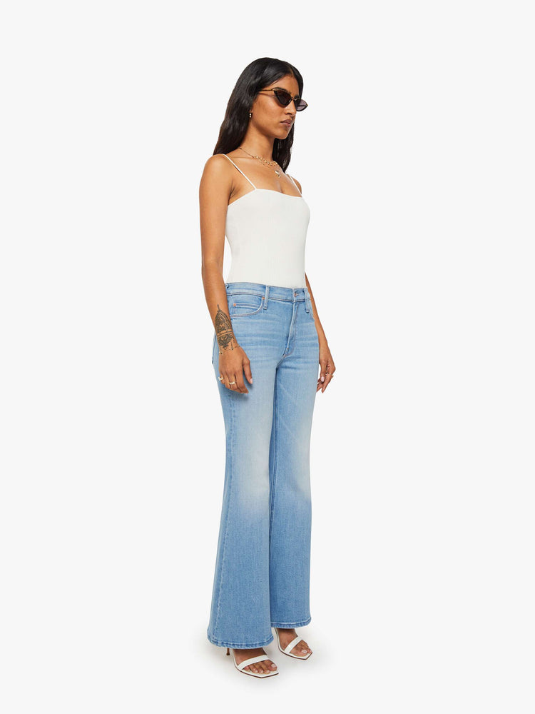Side angle view of a woman in a light blue  high-rise flare with a zip fly, long 30-inch inseam and a clean hem. 