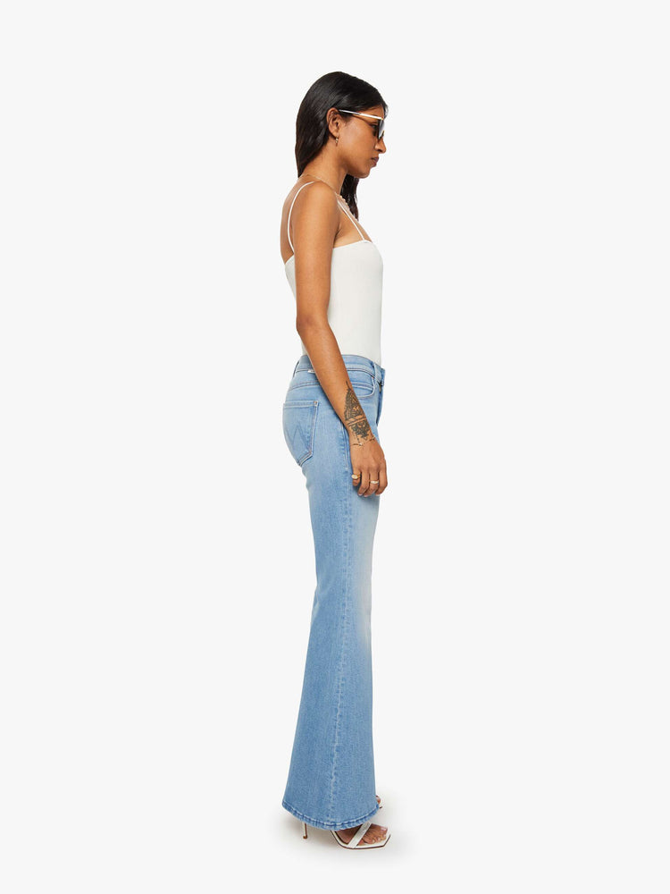 Side view of a woman in a light blue  high-rise flare with a zip fly, long 30-inch inseam and a clean hem. 