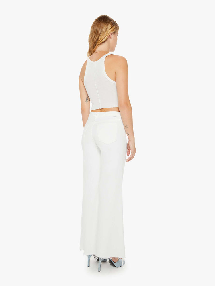 Back view of a woman petite white denim high-waisted wide leg has a full-length inseam and a frayed hem.