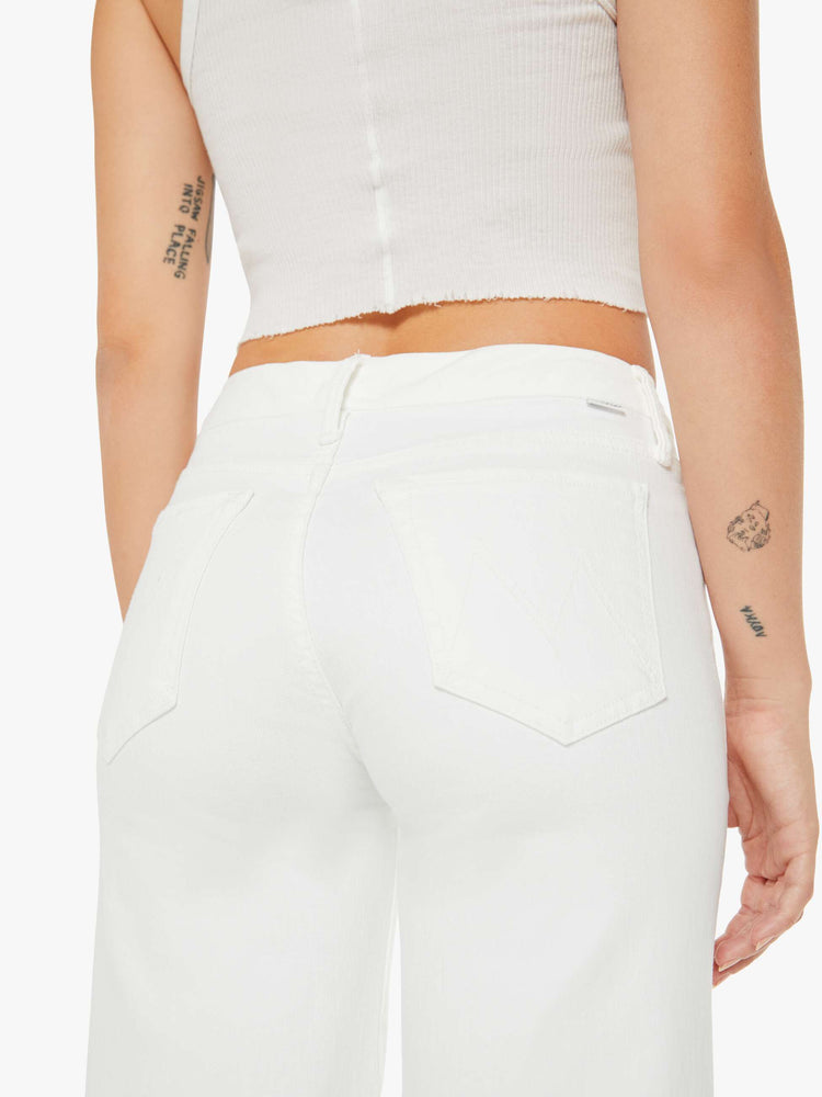 Waist close up view of a woman petite white denim high-waisted wide leg has a full-length inseam and a frayed hem.