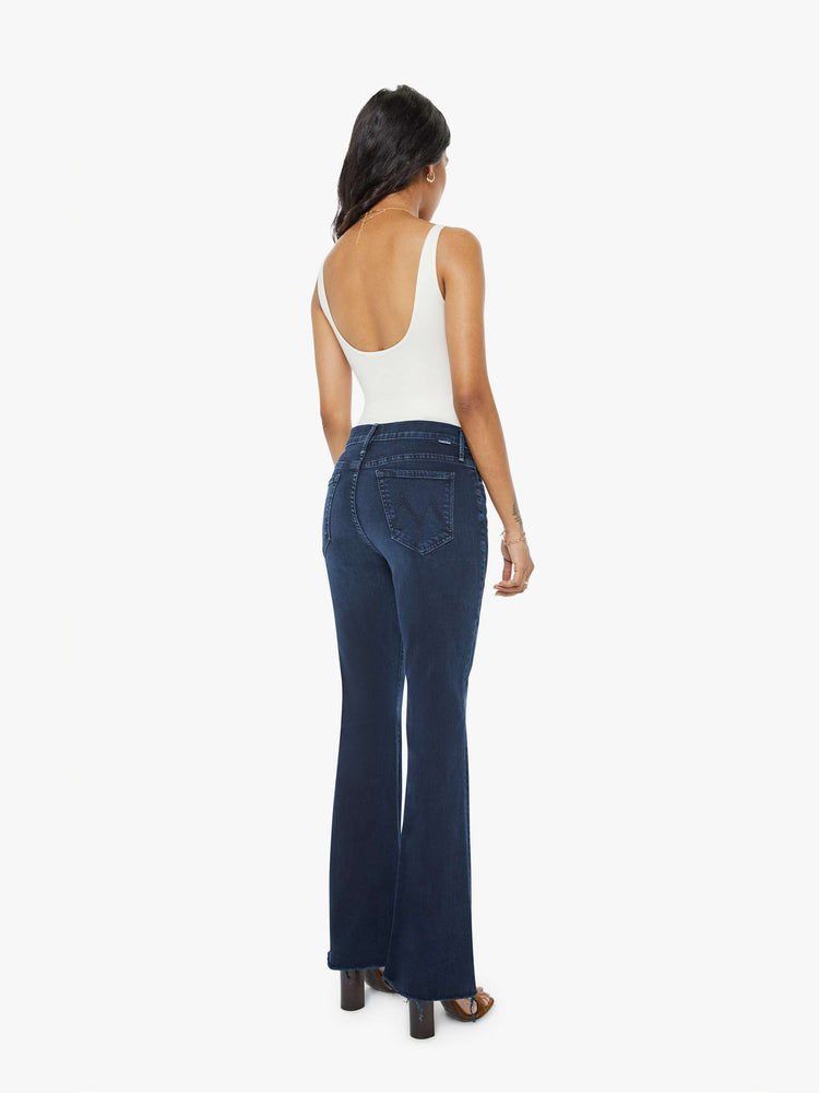 Back  view of a dark blue mid-rise flare has a 29-inch inseam with a frayed hem.