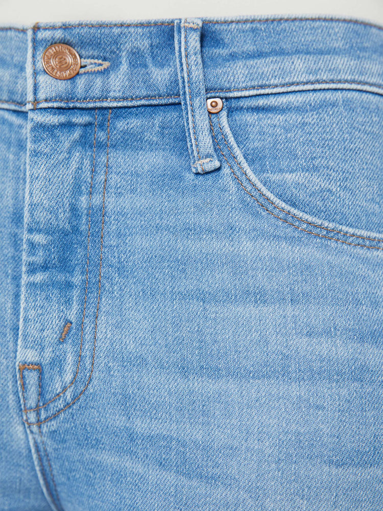 Swatch view of a petite woman in a light blue mid-rise flare has a zip fly, 28-inch inseam and a frayed hem. 