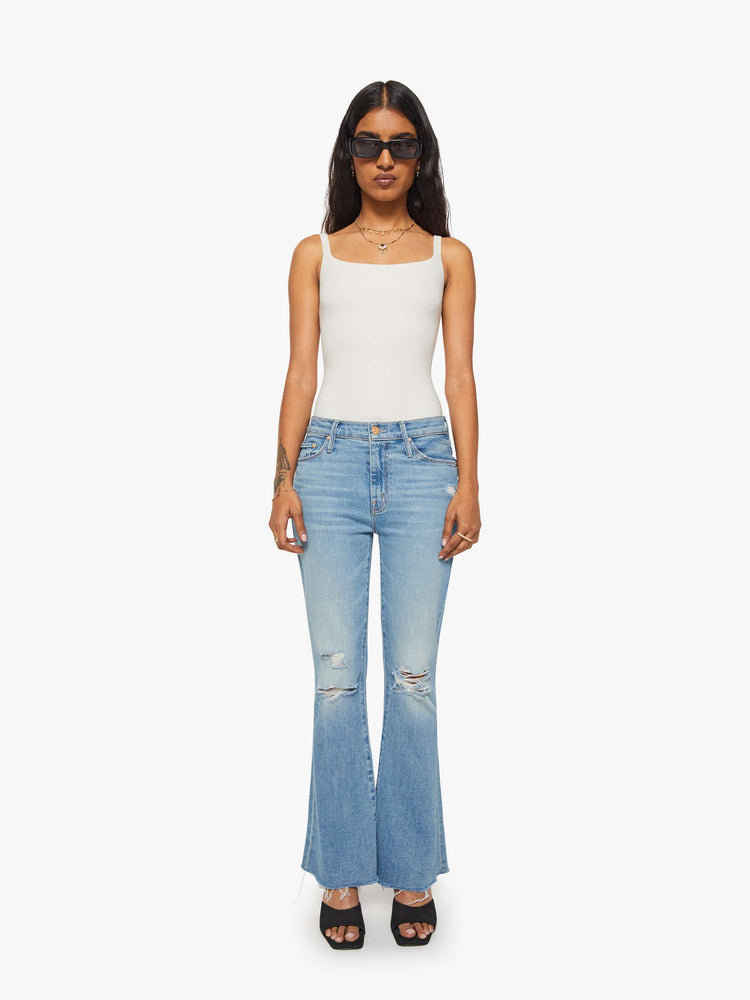 Front view of a woman mid-rise flare has a zip fly, 28-inch inseam and a frayed hem.
