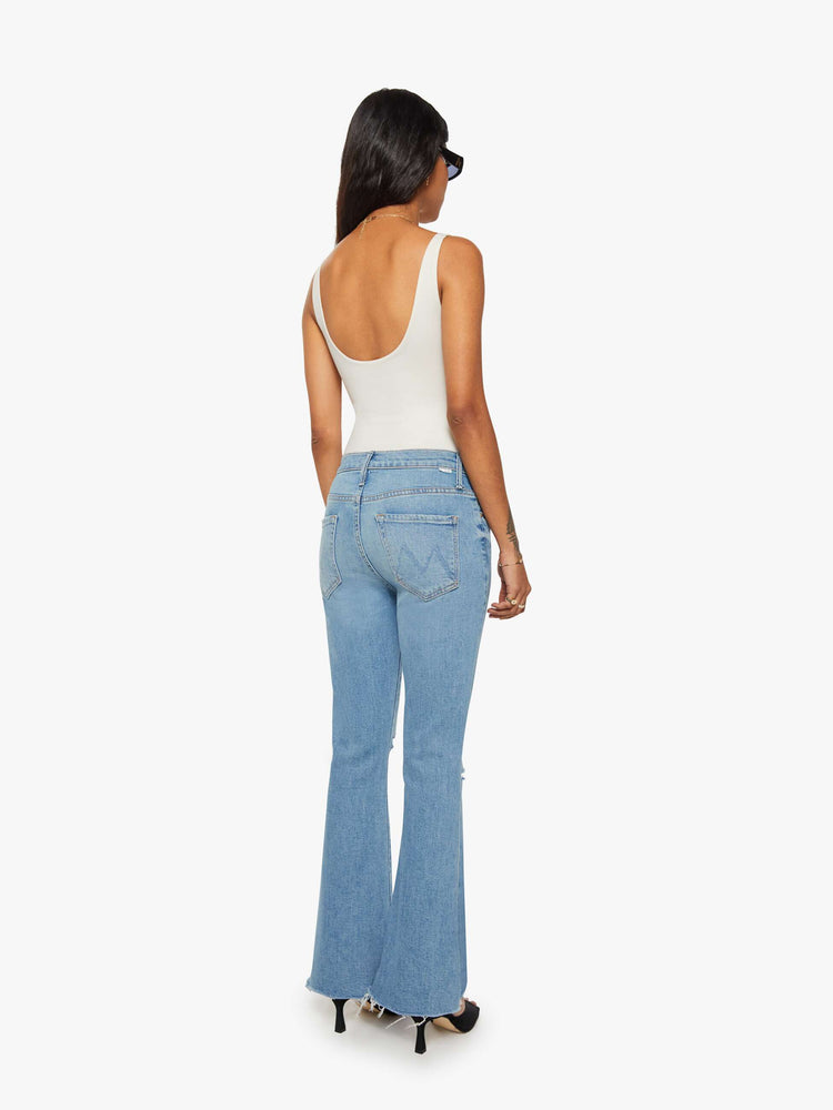 Back view of a woman mid-rise flare has a zip fly, 28-inch inseam and a frayed hem.
