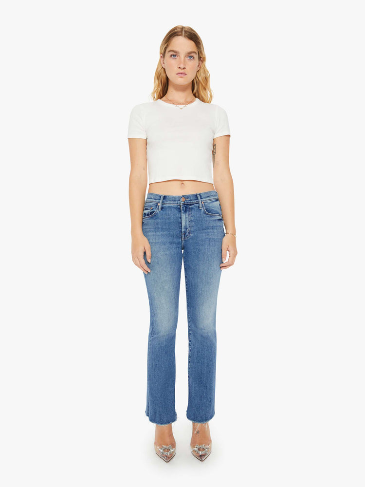 Front view of a petite womans flare jean has a mid rise with a sneaker-length inseam and a frayed hem in a medium blue wash.