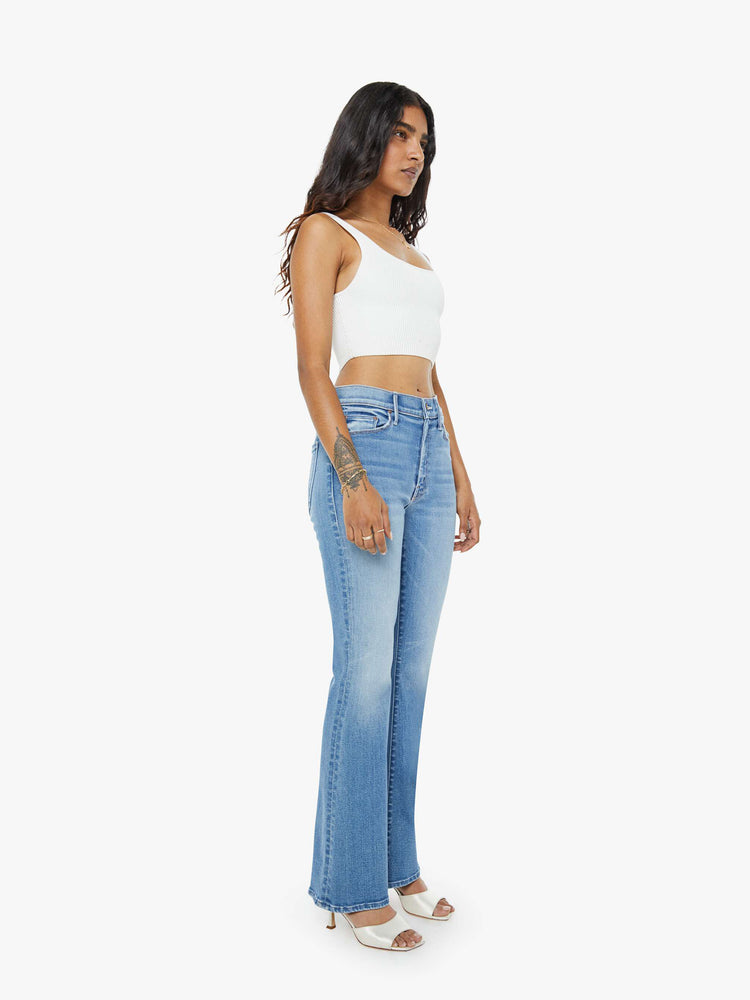 Front view of a petite woman flare jean has a mid rise with a sneaker-length inseam and a clean hem in mid-blue wash.