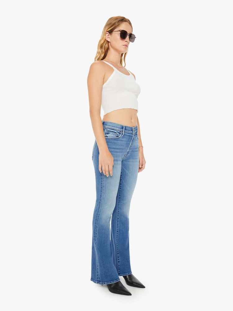 Front view of a petite woman flare jean has a mid rise with a sneaker-length inseam and a clean hem in mid-blue wash.