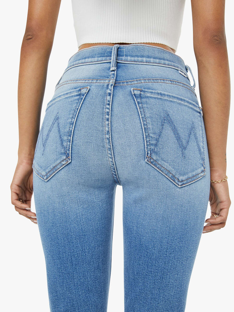 Waist view of a petite woman flare jean has a mid rise with a sneaker-length inseam and a clean hem in mid-blue wash.