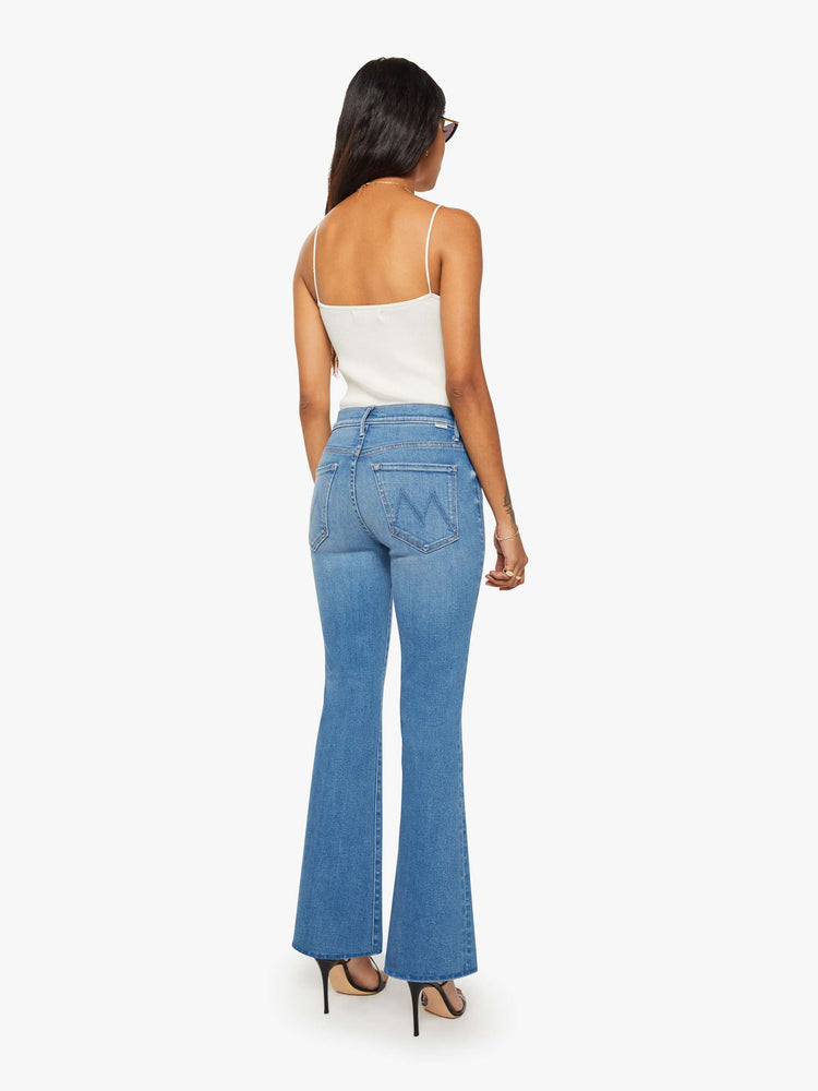 Back view of a petite woman in a mid blue mid rise with a 28-inch inseam and a clean hem.