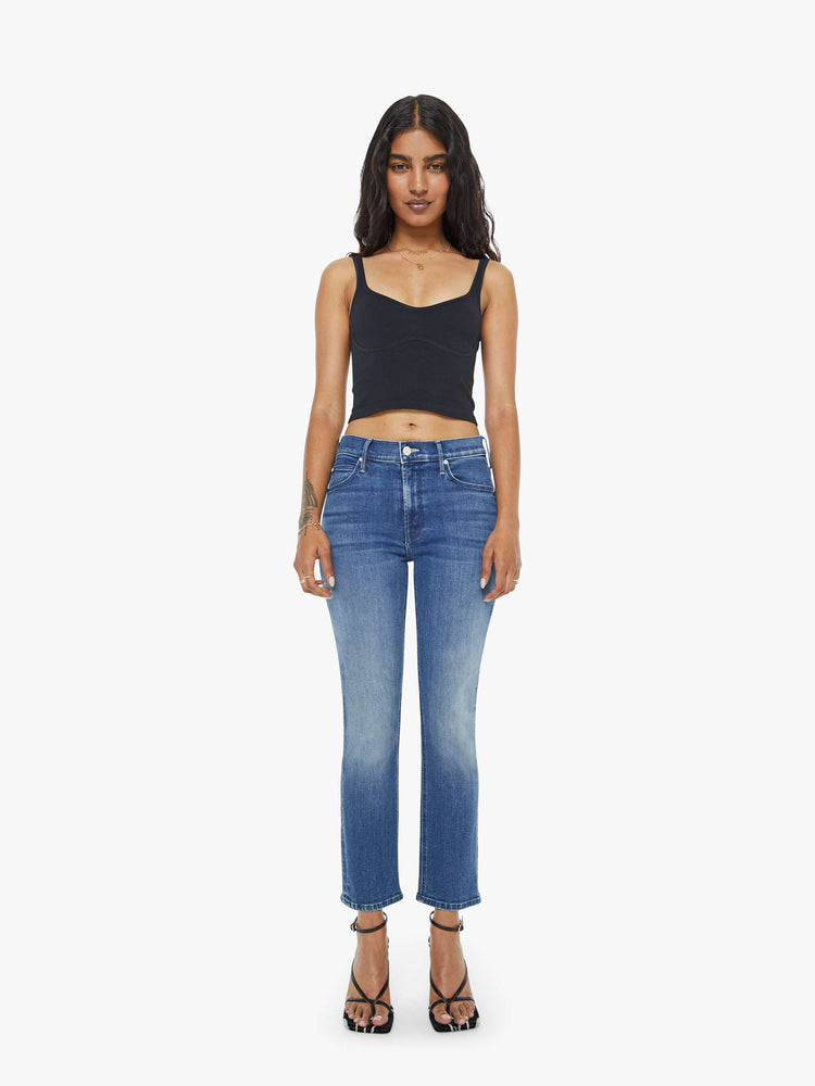 Front view of a petite woman mid-rise straight leg jean its at the ankle with a clean hem in a mid blue wash.