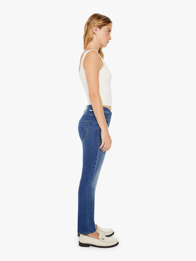 Side view of a petite woman mid-rise straight leg jean its at the ankle with a clean hem in a mid blue wash.