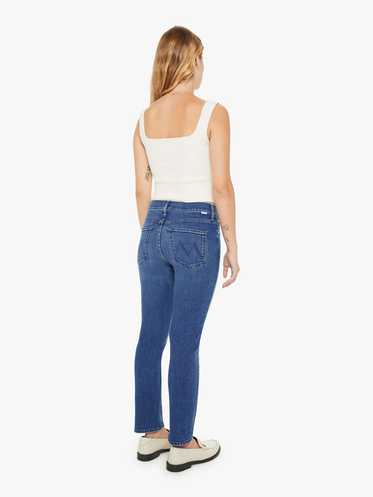 Back view of a petite woman mid-rise straight leg jean its at the ankle with a clean hem in a mid blue wash.