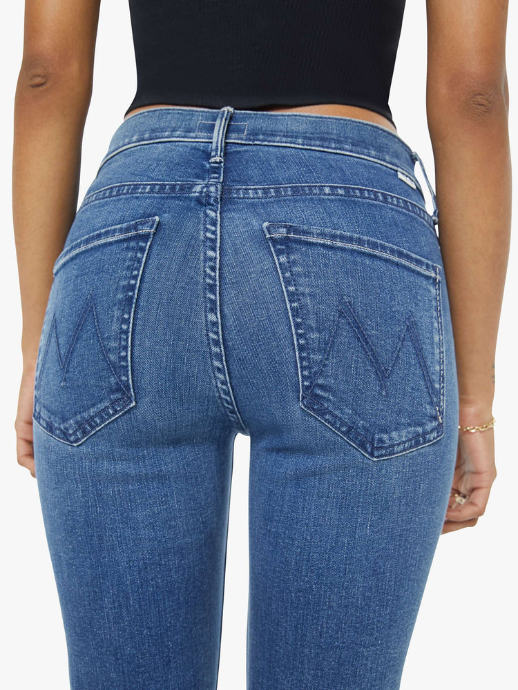 Close up back view of a petite woman mid-rise straight leg jean its at the ankle with a clean hem in a mid blue wash.