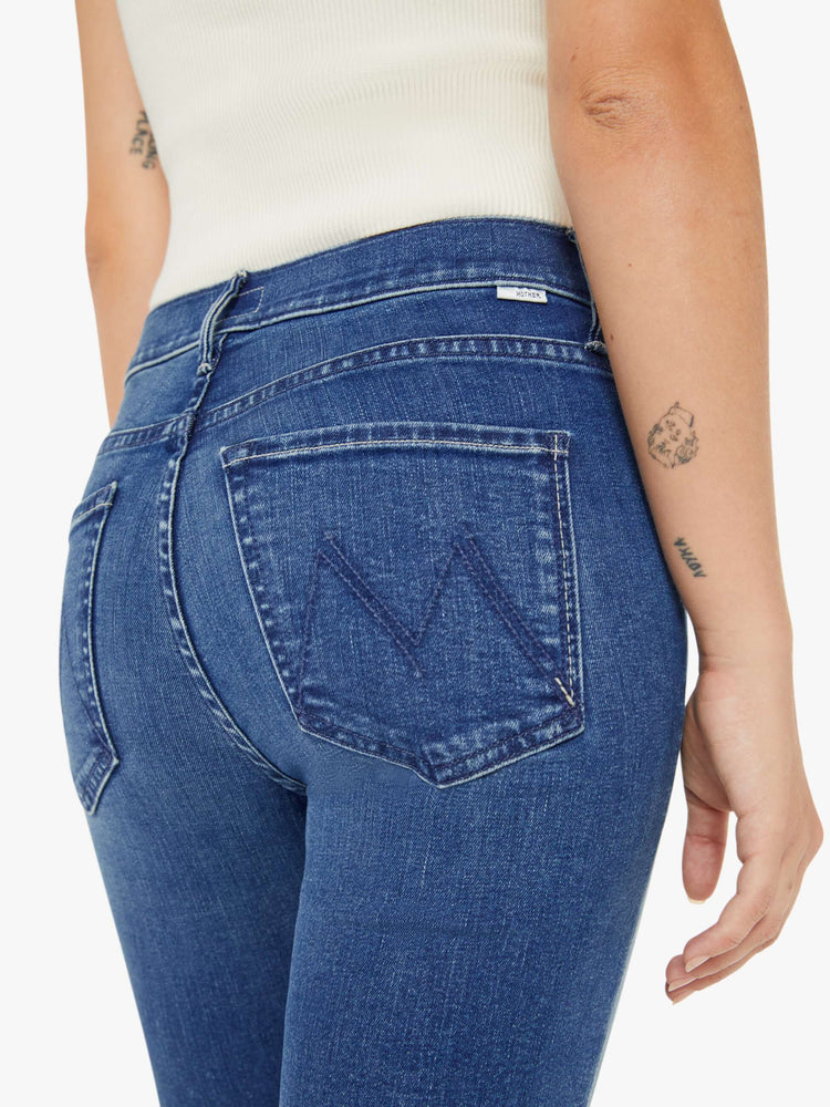Close up back view of a petite woman mid-rise straight leg jean its at the ankle with a clean hem in a mid blue wash.