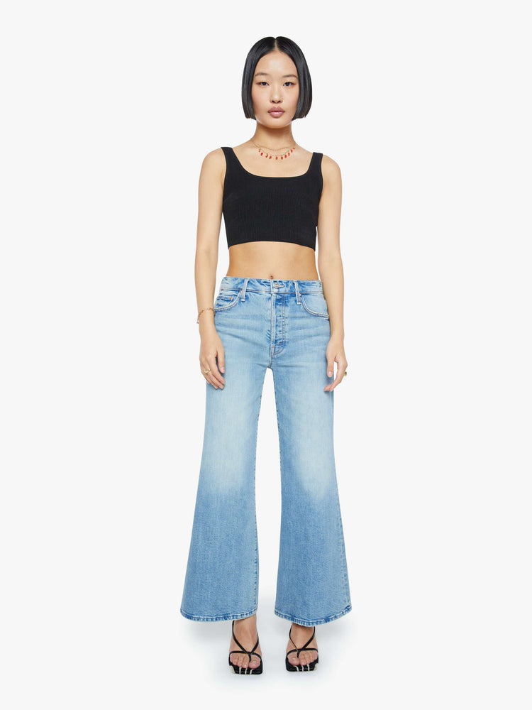 Front view of a woman in a light blue high-waisted wide-leg jeans with a button fly, 29-inch inseam and clean hem.