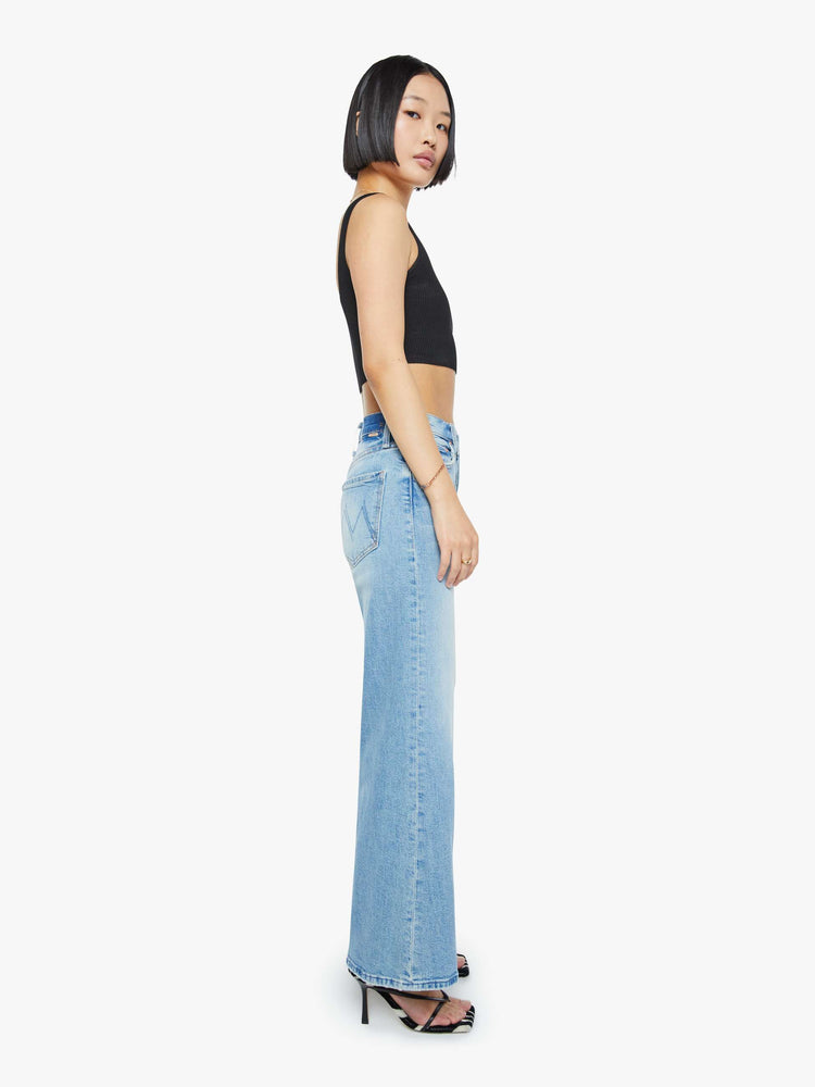 Side view of a woman in a light blue high-waisted wide-leg jeans with a button fly, 29-inch inseam and clean hem.