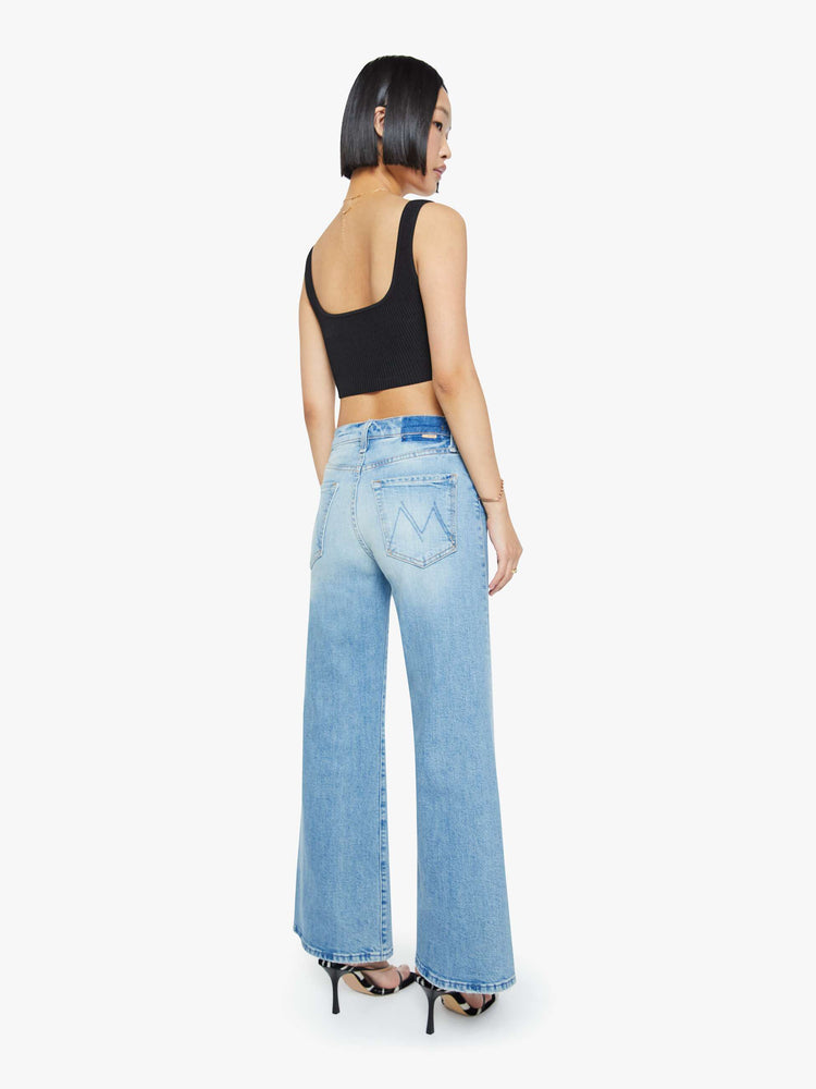 Back view of a woman in a light blue high-waisted wide-leg jeans with a button fly, 29-inch inseam and clean hem.