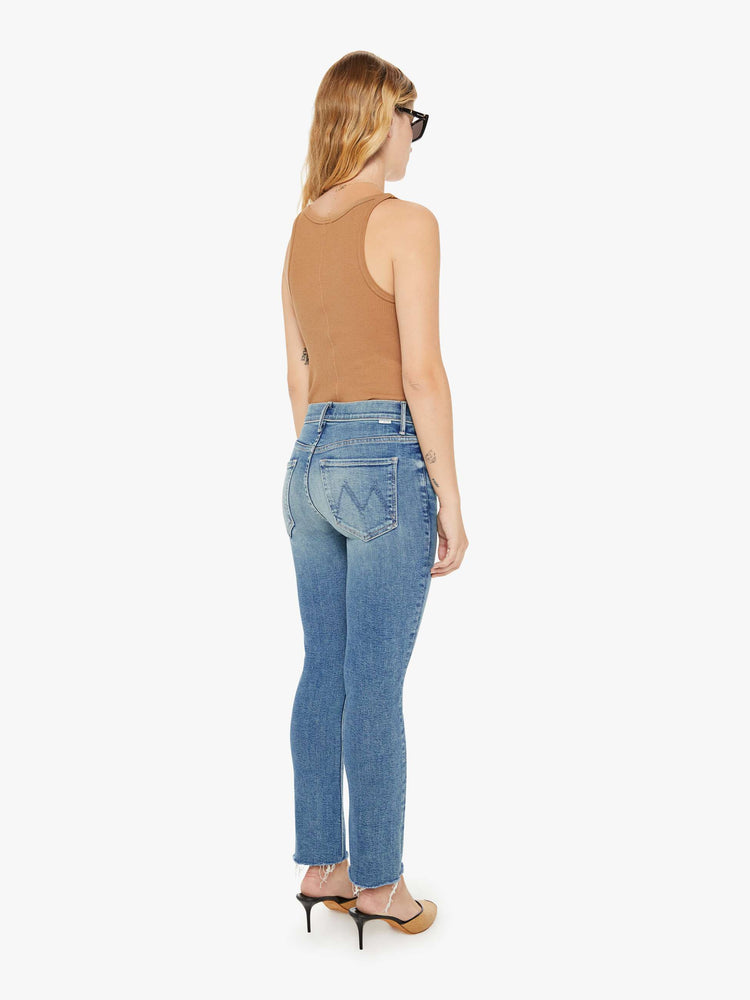 Back view of a womens mid rise jean in a medium blue wash, featuring an ankle fray.