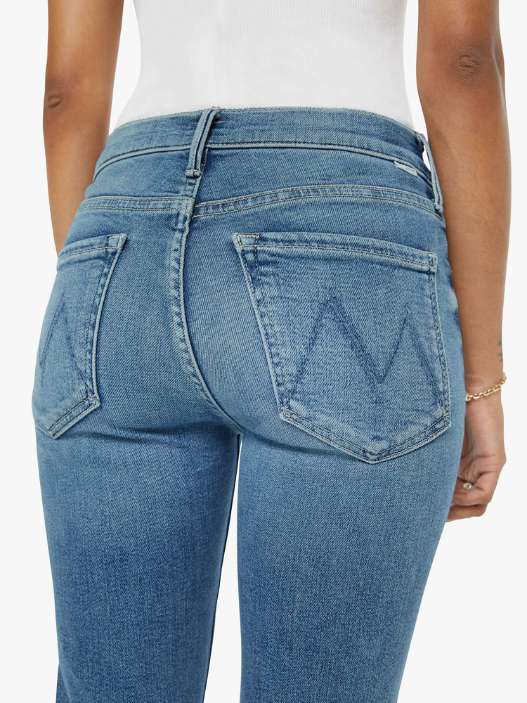 Back close up view of a womens mid rise jean in a medium blue wash, featuring an ankle fray.