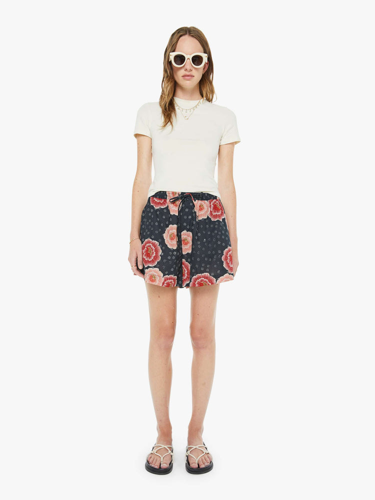 Front view of a woman in a pink poppy blue shorts with an elastic waist, side slit pockets, a slightly curved hem and loose, flowy fit.