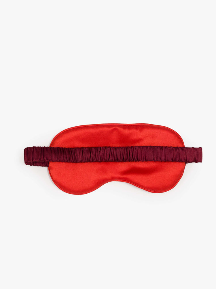 Back view of a red sleeping mask with two heart charms on the front.