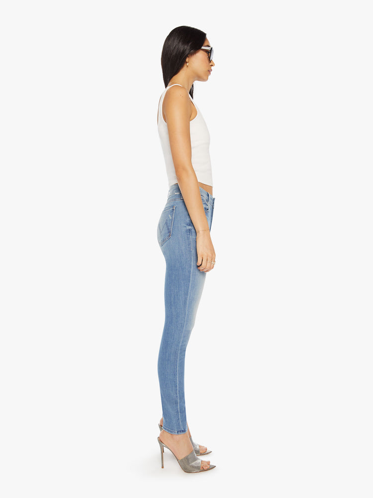 Side view of  a womens light blue denim jean featuring a mid rise, skinny leg, and a clean hem.