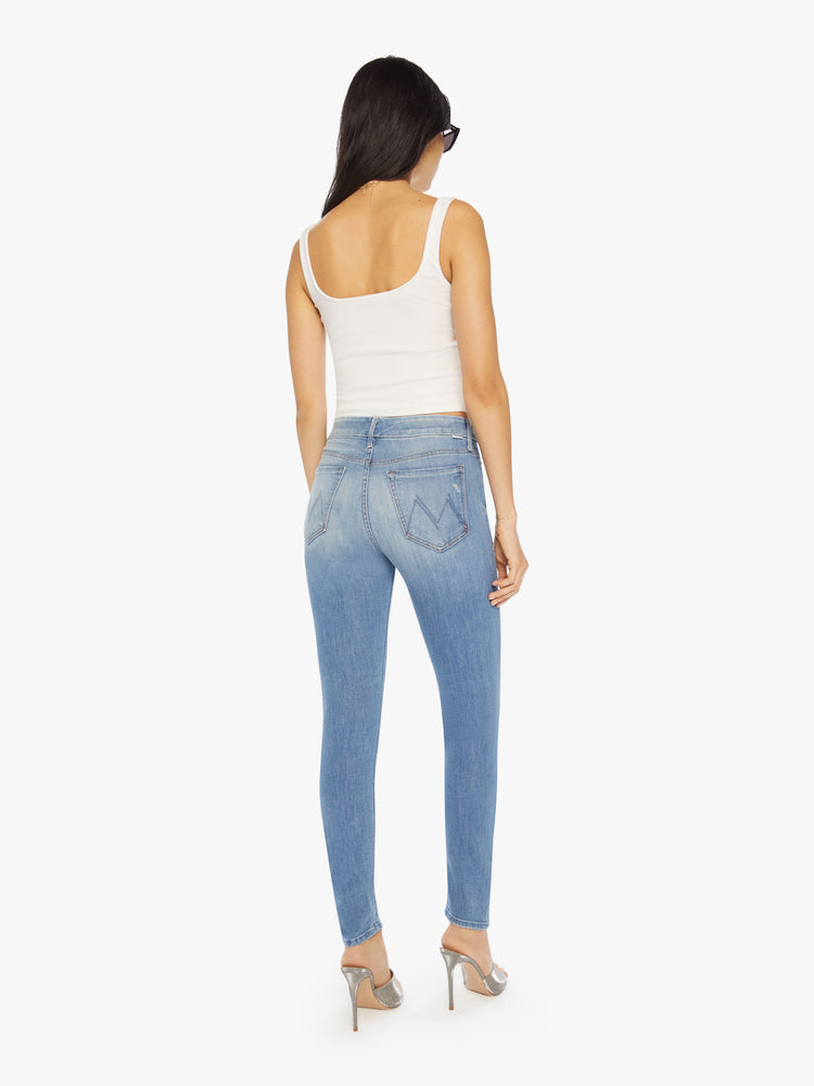 Back view of  a womens light blue denim jean featuring a mid rise, skinny leg, and a clean hem.