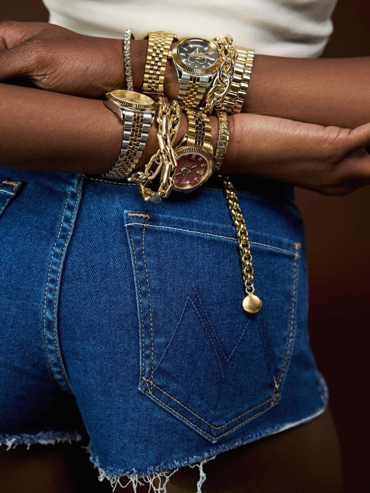 Editorial view of a woman in a  midblue high-waisted denim shorts with a zip fly, short inseam and frayed hem.