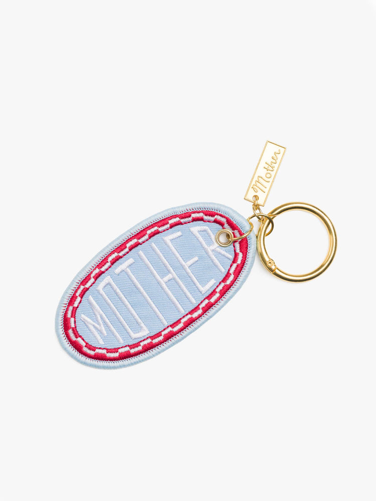 Flat view baby blue, red and white, the keychain features an embroidered patch with MOTHER's name on one side and a smiley face on the other.