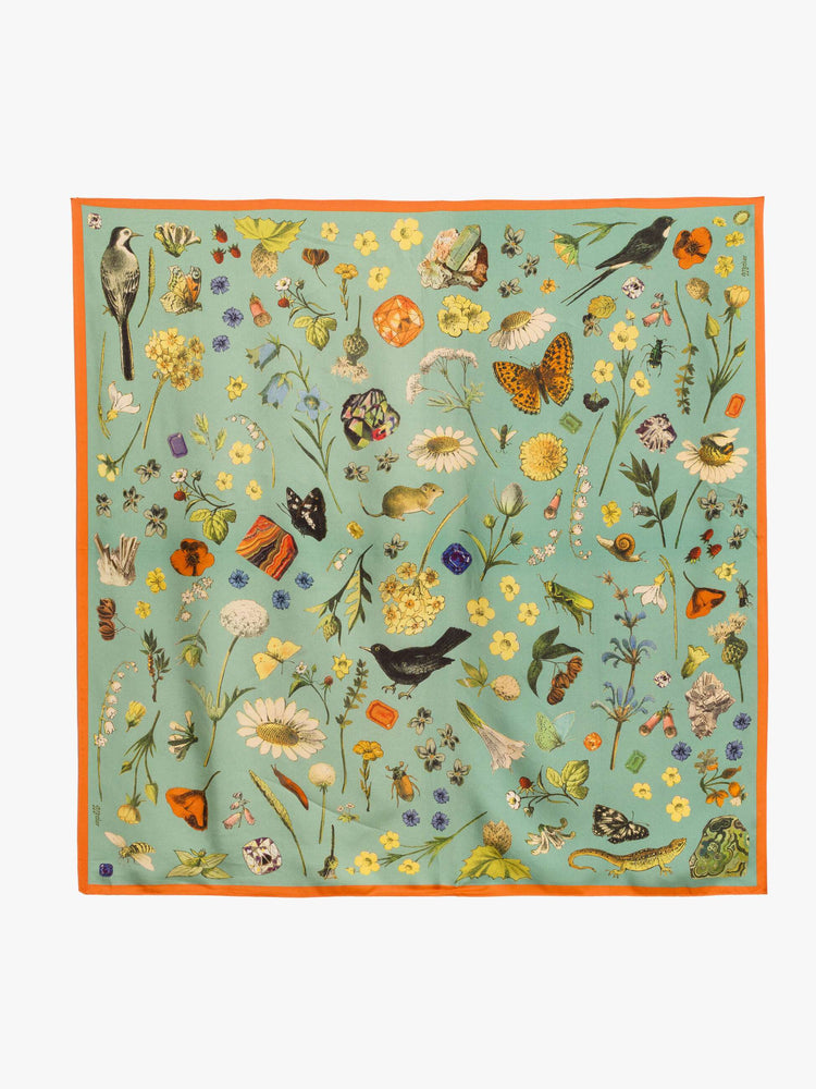 Flat view of a teal-green scarf with oversized printed flowers, gems, and creatures throughout.