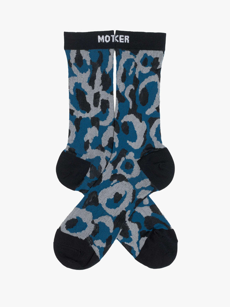 Side angle view of classic tube socks with an explicit message from MOTHER. The socks are designed in a translucent blue, grey and tan oversized leopard print with black trim and text in white.