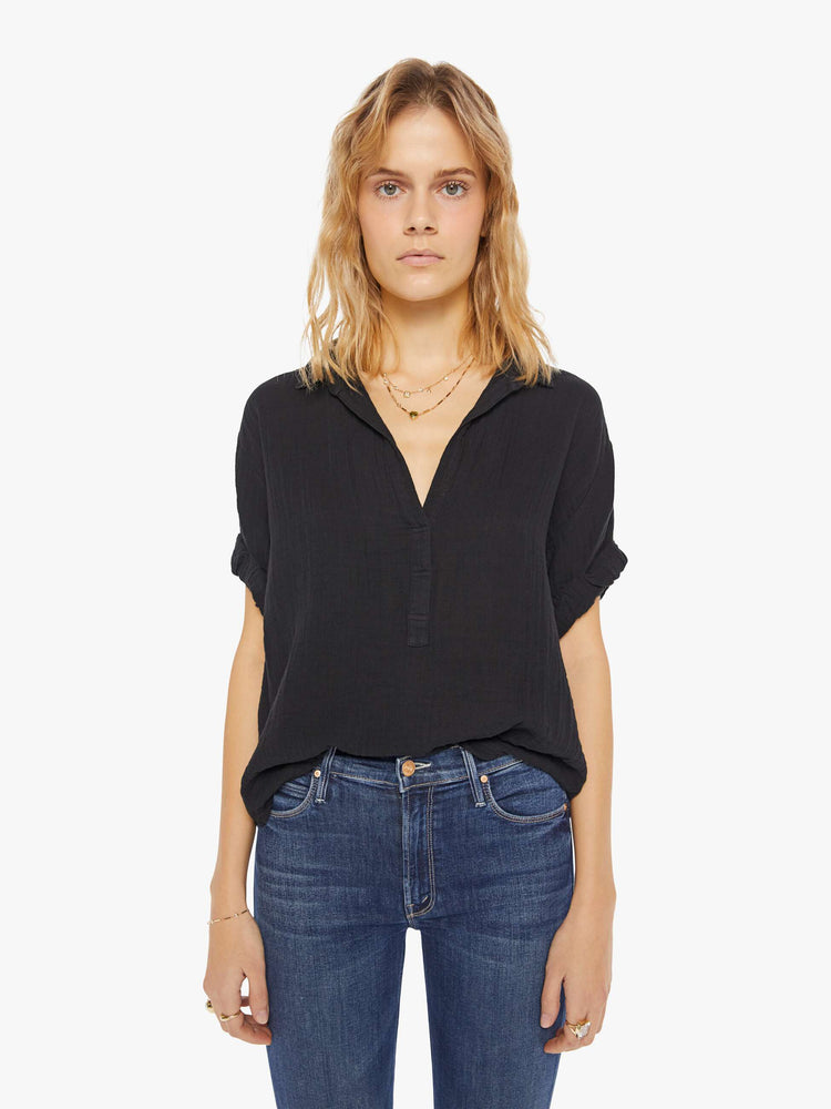 Womens front view of a collared, black, V-neck shirt with rolled elbow-length sleeves and a slightly boxy fit.