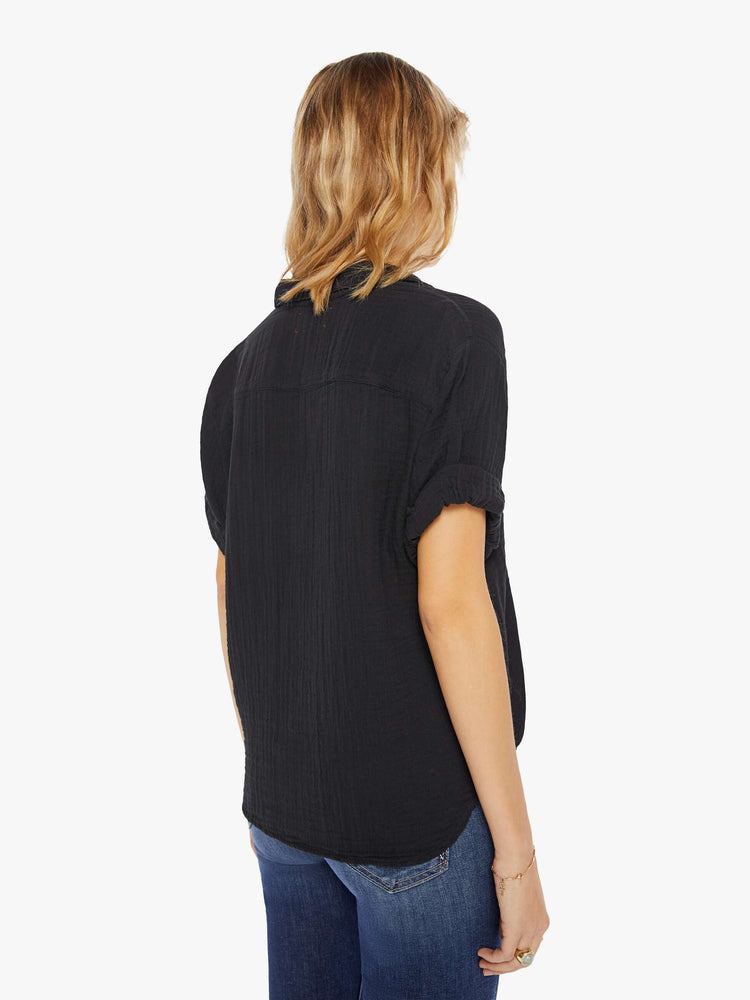 Womens back view of a collared, black, V-neck shirt with rolled elbow-length sleeves and a slightly boxy fit.