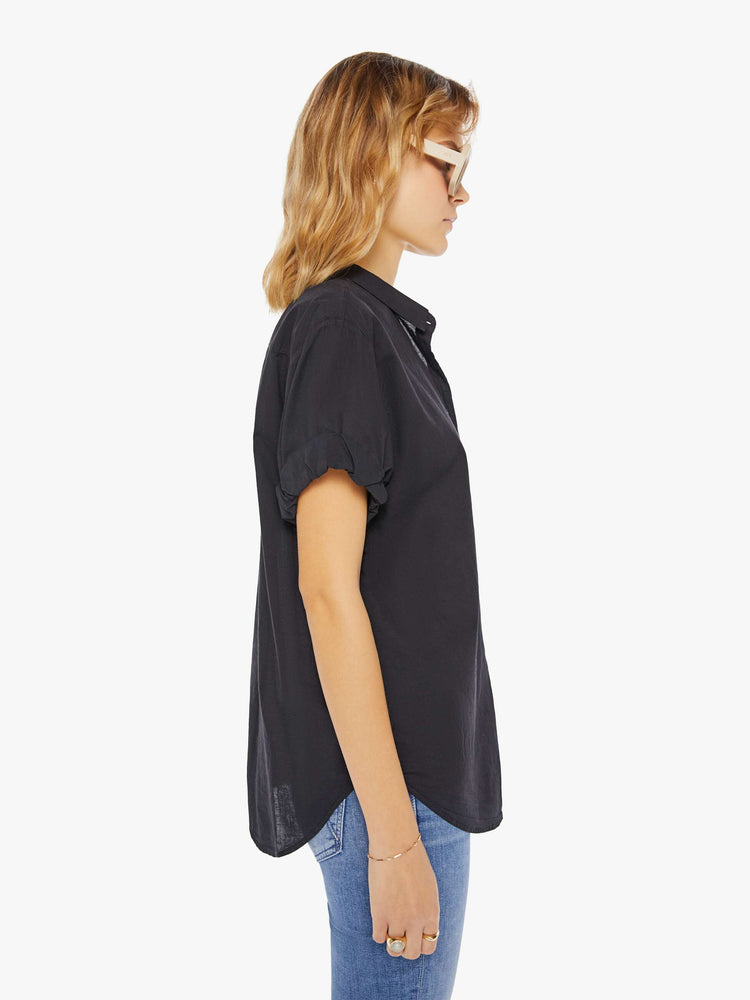 Side view of a woman wearing a black short sleeve button up shirt