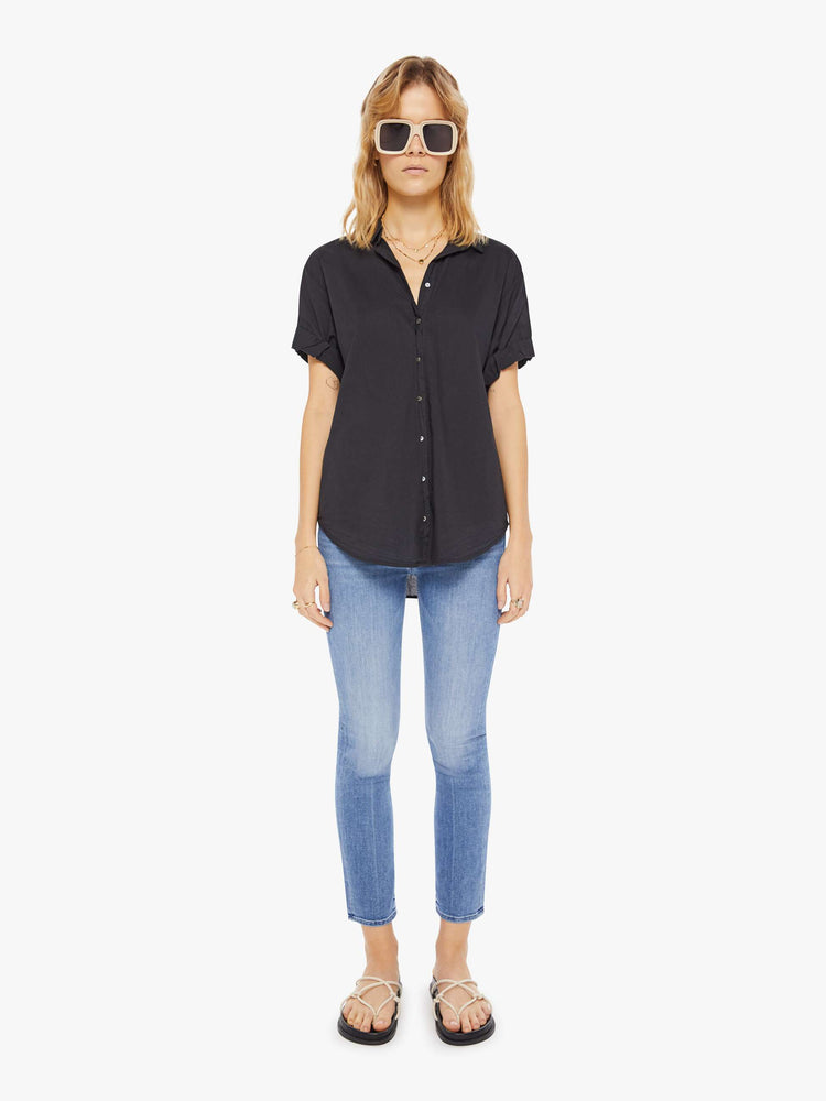 Full body view of a woman wearing a black short sleeve button up shirt