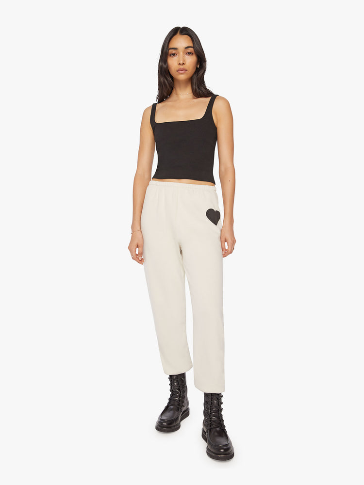 Full body front view of a Womens white sweatpant with a black heart graphic printed on the left side hip.