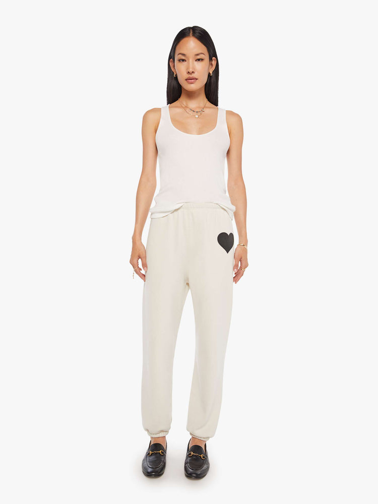 Full body front view of a Womens white sweatpant with a black heart graphic printed on the left side hip.