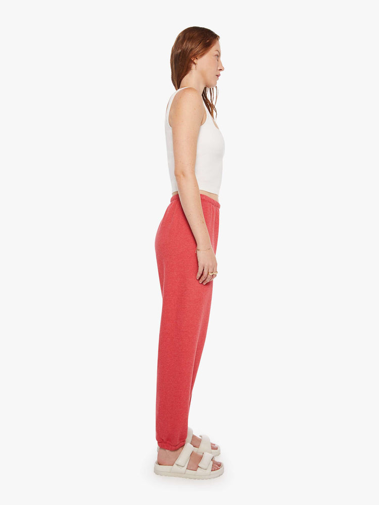 Side view of a woman in red sweatpants have an elastic waist and cuffs for a loose, comfortable fit.