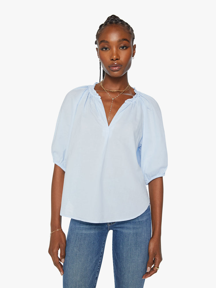 Front view of woman light blue hue blouse features a ruffled collar with a deep V-neck, elbow-length balloon sleeves and a loose fit.