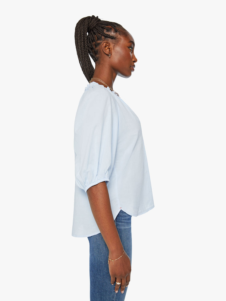 Side view of woman light blue hue blouse features a ruffled collar with a deep V-neck, elbow-length balloon sleeves and a loose fit.
