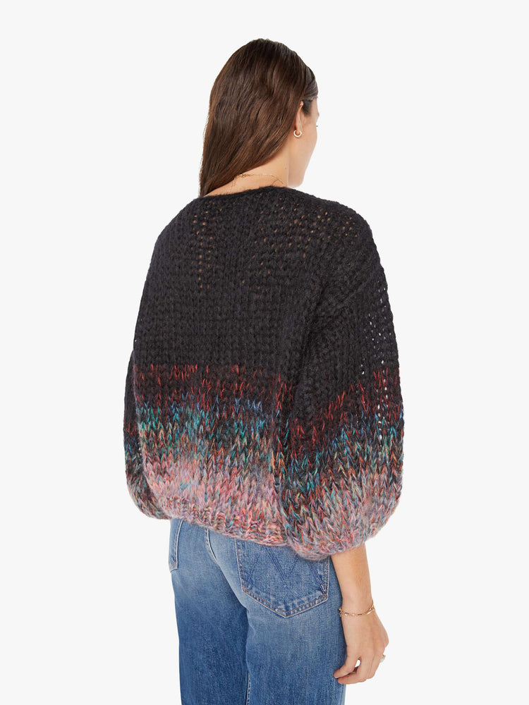 Back view of a womens chunky knit sweater featuring a black to multi color gradient and billow sleeves.