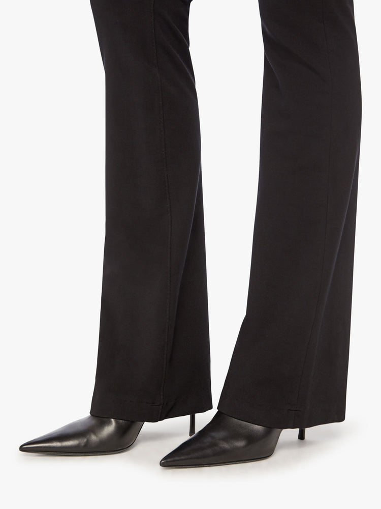 Side close up view of a womens black high rise pant featuring a fitted flare leg.